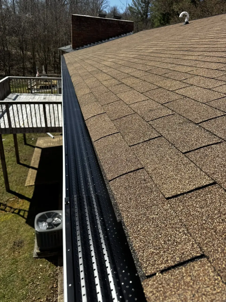 Micro-mesh gutter guard installed along a shingle roof edge